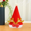 Red velvet Christmas hat with gold antlers and snowflake pattern on a wooden surface - Kids Gold Reindeer Antlers