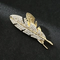Detailed macro view of a golden feather brooch with crystal rhinestones on black background - Feather Gold