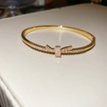 Vue macro du bracelet doré avec un nœud étincelant serti de zircons cubiques - Forme de nœud papillon / Or
