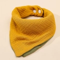 Detail of double-sided muslin cotton baby bib in mustard yellow and olive green colors - Ginger + Army Green