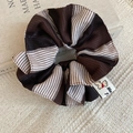 Close-up of a striped brown fabric scrunchie featuring a dog label on textured linen - 1# Brown and White Striped Scrunchie
