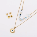 Close-up of golden necklace and stud earrings set with blue evil eye charms - Gold White