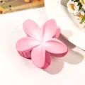 Close-up of a matte pink flower hair claw clip on a white surface with daisy decor - Gradient Pink