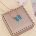 Golden chain necklace featuring a blue crystal butterfly pendant on a beige gift box - Blue