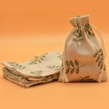 Beige linen drawstring bags with green leaf print, shown as a flat stack and upright bag - Green Leaf