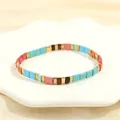 Detail of bohemian Tila bead bracelet with colorful enamel tiles on white ceramic plate - Multicolor J-Blue Red Pink Brown Black Gold