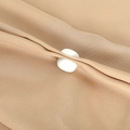 Detailed macro view of a white round fastener secured on light brown textured fabric - White