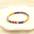Detail of colorful enamel tile Tila bracelet with gold accents on a white shell tray - Multicolor G-Yellow Orange Purple Red Blue Gold