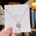 Silver bow necklace with sparkling zircon pendant held against a thank you card - Bow / Silver