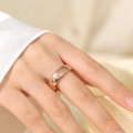 Close-up of a wide polished rose gold stainless steel ring worn on a finger - US 6 / Rose Gold