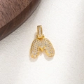Close-up of golden letter M pendant with micro-paved cubic zirconia on textured background - M