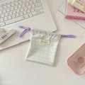 Detail of green plaid drawstring storage bag with a fabric logo on a desk with stationery - Soft Purple Plaid