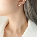Eleganti orecchini a cuore dorati con inserto in madreperla indossati da una modella - Oro