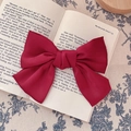 Vintage French oversized red satin bow hair clip placed on an open book for styling - Bow Spring Clip / Red
