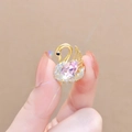 Macro detail of golden swan earring with pink pear-cut gemstone and crystal accents - Pink Swan
