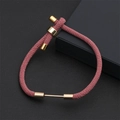 Détail du bracelet en corde de Milan tissé rose avec fermoirs dorés sur cuir noir texturé - Rose