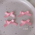 Close-up of four mini 3cm pink satin bow hair clips on a decorative ceramic plate - Light Pink
