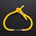 Detail of yellow braided rope bracelet with golden metal charms and adjustable slide knot - Yellow