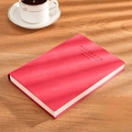 Red leather A5 notebook with debossed text on a wooden desk with a coffee cup - Ruled / A5-Red