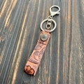 Close-up of Western-style embossed brown leather keychain with sunflower rivet and lobster clasp - Style 6 (Sunflower B)