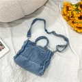 Dettaglio di una piccola borsa a tracolla in denim blu con cinturino regolabile e manico - Azzurro