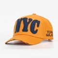 Dettaglio ravvicinato di un cappellino da baseball arancione con scritta NYC applicata blu - Giallo