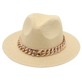 Détail d'un chapeau Panama beige avec une grosse chaîne en or rose et texture en paille tressée - Chapeau de Paille à Bord Plat / Beige