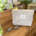 Cream corduroy makeup bag with letter patch on a wooden desk setting - Makeup Bag / Milk Tea