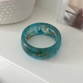 Close-up of blue marble resin bangle on a white minimalist background with elegant props - Smudged Cyan