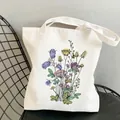 White canvas tote bag featuring colorful wildflower garden illustration on a black chair - C11 Pink Botanical Illustration