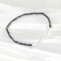 Natural dark gray faceted bead bracelet with silver cross charm on white silk background - Silver Plated Grey
