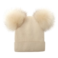 Close-up of cream knit beanie featuring dual fluffy faux fur pom-poms and ribbed texture - Beige