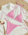 Close-up of pink ribbed bikini set with tie-up straps and beach accessories - Pink