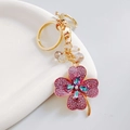 Close-up of golden four-leaf clover keychain with pink rhinestones and colorful crystals - Purple