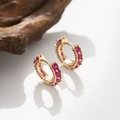 Detailed macro view of gold-plated hoop earrings featuring inlaid pink zircon stones - Red Synthetic Gemstone