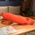 Realistic orange arowana plush fish pillow on a wooden table in a cozy home setting - Red Arowana