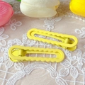 Close-up of yellow wavy hair clips on white lace with decorative flowers - Yellow