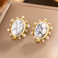 Macro shot of oval gold stud earrings with marble stone and pearl accents - E-341 / Gold White Marble