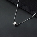 Collier minimaliste avec pendentif cube argenté et chaîne box sur fond de pierre sombre - boîte chaîne