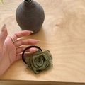 Detailed view of hand holding a fabric rose hair tie in army green with elastic band - Withered Rose Hair Tie-Green
