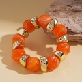 Detail of orange marble resin beads and irregular gold metal spacers on a beaded bracelet - Orange