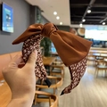 Brown fabric headband with large leopard print bow design shown in a hand-held view - Dark Brown Leopard Bow (FK-B199)
