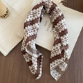 Close-up of printed silk scarf with geometric patterns on a vintage book - Brown Headscarf Style 3