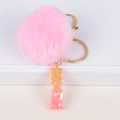 Close-up of pink fluffy pompom keychain with resin gold foil letter pendant detail - Letter I