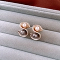 Detail view of gold shell-shaped earrings with champagne and black pearls on velvet - Wavy Shell Two-Tone Pearl Earrings