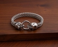 Close-up of vintage punk silver bracelet with double skull clasp on a dark wooden surface - Skull