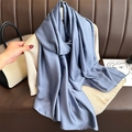 Detail of elegant blue satin silk scarf with a smooth texture draped on a beige sweater - Gray Blue