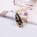 Miniature koi fish crystal ornament with gold foil and black stones on a white surface - Obsidian