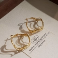 Irregular geometric gold hoop earrings with twisted design in a wooden jewelry box - Gold
