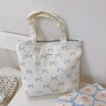 Detail of white canvas tote with blue bow pattern and simple wish label text - White Base Light Blue Bow
